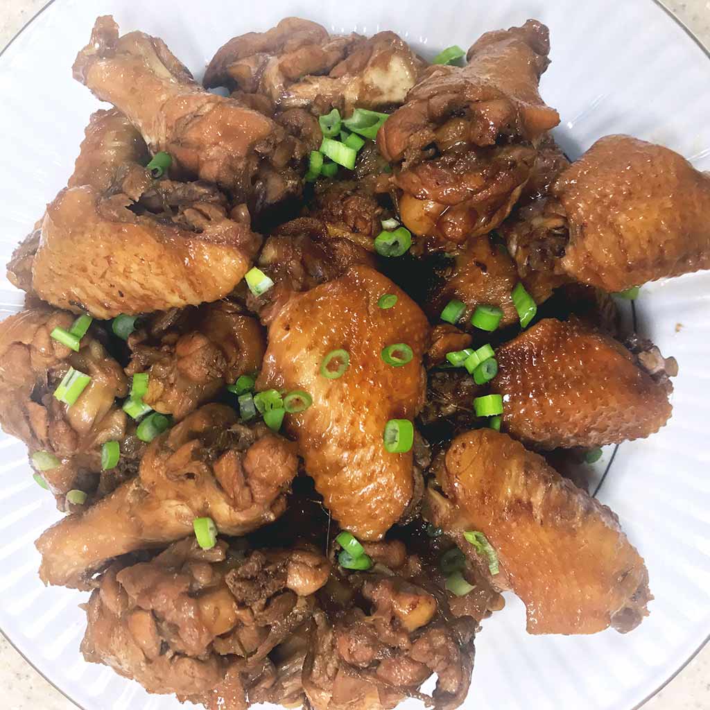 braised chicken wings using soy sauce and coco-cola, garnish with spring onion.